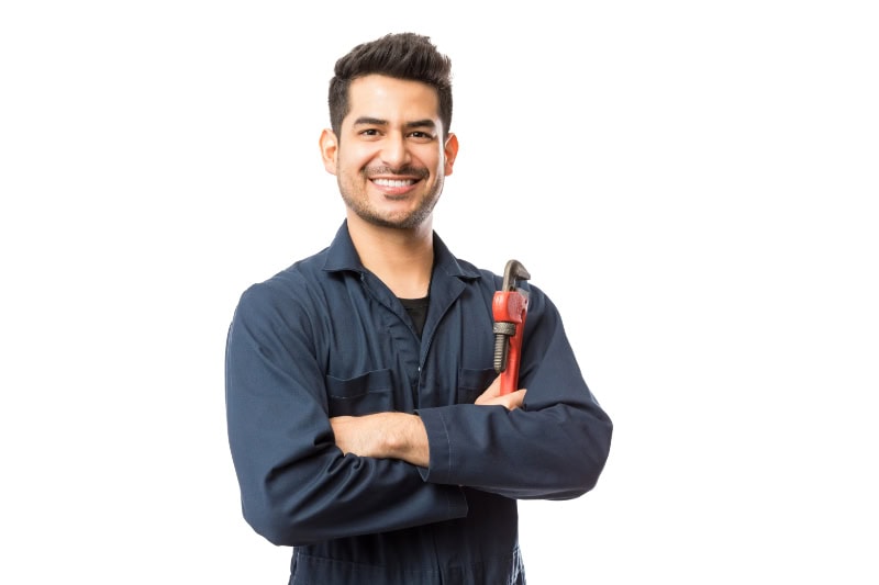Portrait of smiling young male plumber with pipe wrench standing arms crossed on white background.