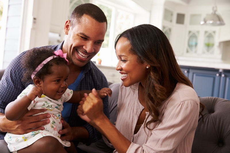 Why Get a Water Filtration System? Happy parents playing with baby dad's knee.